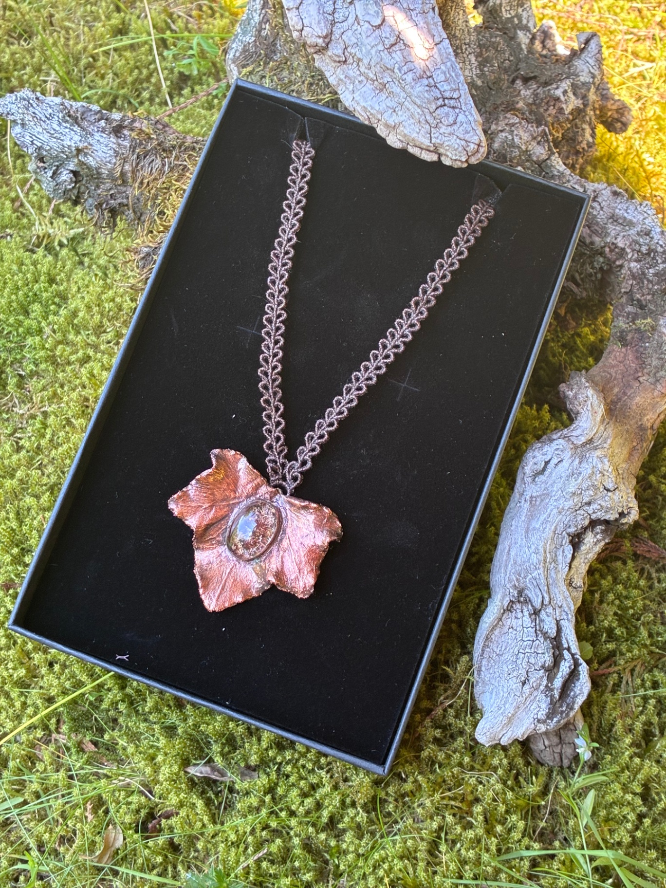 Pendentif fleur cuivrée reposant dans son écrin noir